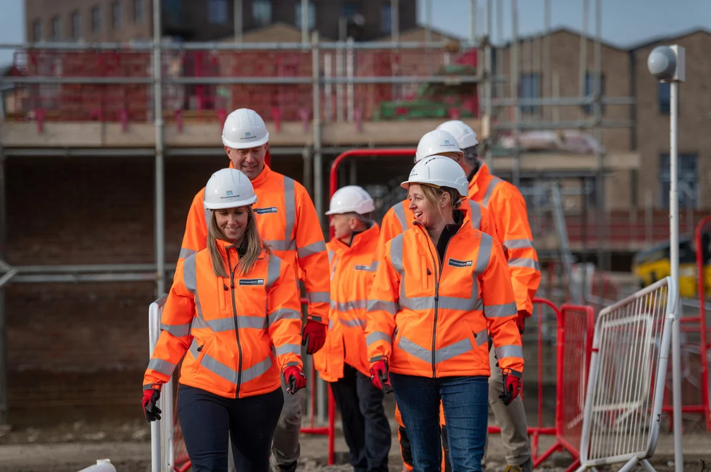 Employees talking together with construction site in the background